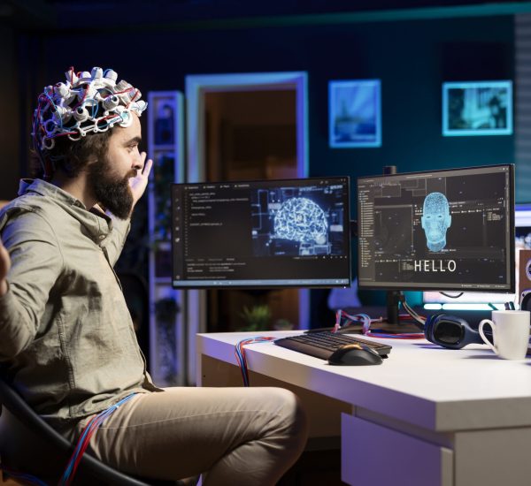 IT professional pleasantly surprised after managing to use EEG headset to communicate with artificial intelligence on computer. Software developer astonished after achieving goal of talking with AI